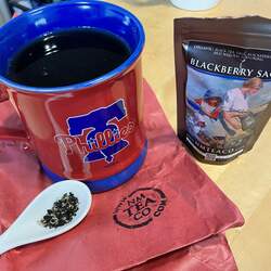 A mug of blackberry sage tea with a bag of the tea next to it.