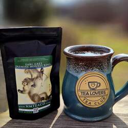 A bag of Earl Grey Jasmine Monkey King tea next to a rustic looking pottery mug that says tea lovers tea club.
