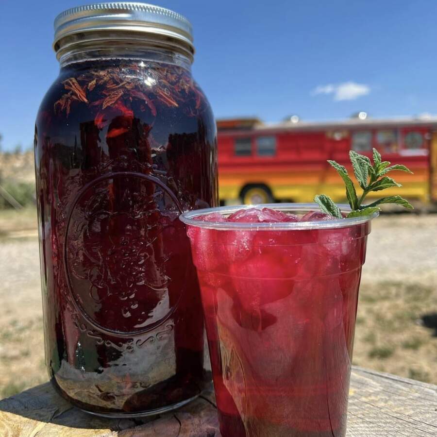 A cup of iced Ruby Refresher with a jar of the brewing sun tea next to it.