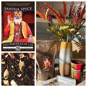 A big bag of Sandia Spice loose leaf tea next to a large vase of red and orange flowers and an Albuquerque mug.